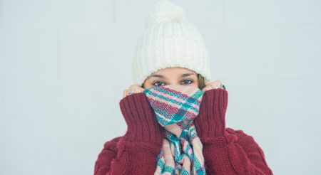 A closeup shot of a girl with her face wrapped up in a scarf on white background